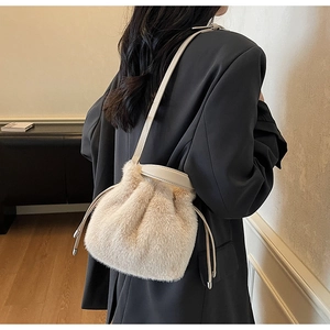 Detail of plush faux fur bucket bag with drawstring and leather strap in beige white