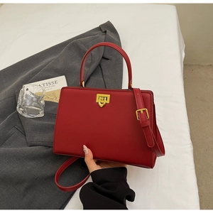 Macro view of a red structured handbag with gold hardware on a stylish fabric background