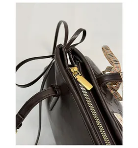 Macro shot of dark brown leather bag with golden zipper and vintage plaid silk scarf handle