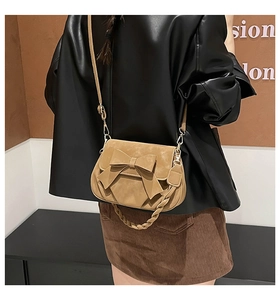 Detail of khaki crossbody bag with large bow decoration and woven handle