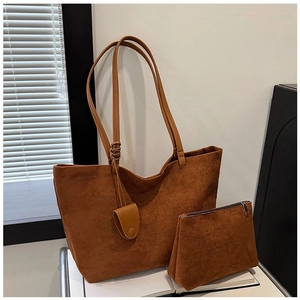 Close-up of caramel brown suede tote bag and matching clutch pouch with knot detail