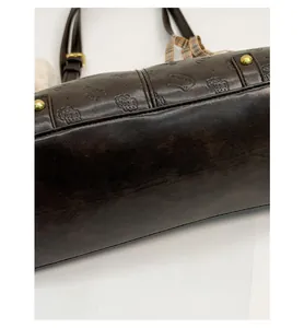Detail view of reinforced bag bottom with gold metal studs and embossed cat patterns