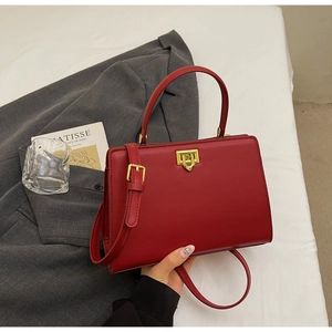 Detail of red vintage leather handbag featuring a golden metal twist lock and smooth texture