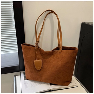 Detailed view of large brown suede tote bag with leather straps on a magazine