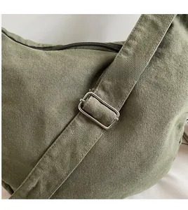 Detail of adjustable metal buckle and thick canvas texture on military green crossbody bag