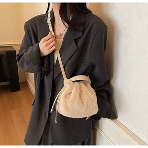 Detail view of beige plush faux fur bucket bag with drawstring and leather strap