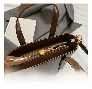Dettaglio della ferramenta dorata e della trama in pelle oliata di questa borsa tote marrone