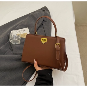 Detail view of structured dark brown handbag with golden twist-lock and elegant handle