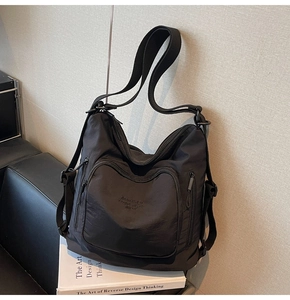 Detail view of the black nylon tote bag showing multiple zipper pockets and fabric texture