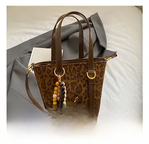 Dettaglio della borsa a secchiello leopardata in pelle scamosciata con logo dorato