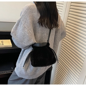 Detail of black plush faux fur bucket bag featuring leather drawstring and strap