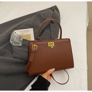 Close-up of brown vintage leather handbag with gold twist lock and adjustable strap