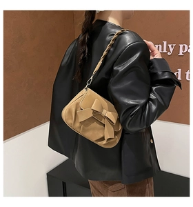 Detail of vintage brown bag with large bow decoration and braided shoulder strap
