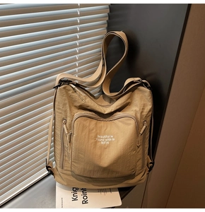 Detail view of khaki nylon tote bag with zipper pockets and white screen print