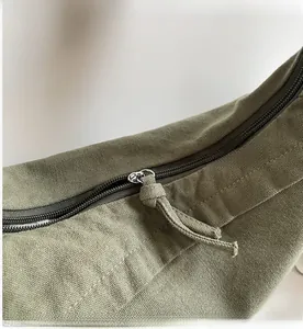 Detail of smooth zipper closure and woven canvas texture on olive green shoulder bag