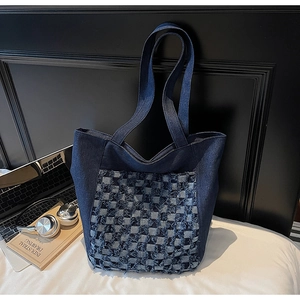 Détail d'un sac cabas en jean bleu avec motif à carreaux effilochés et grand volume