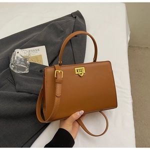Detail of caramel leather handbag with vintage gold buckle and adjustable strap