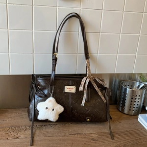 Close-up of brown tote bag with embossed cat patterns and star plush keychain
