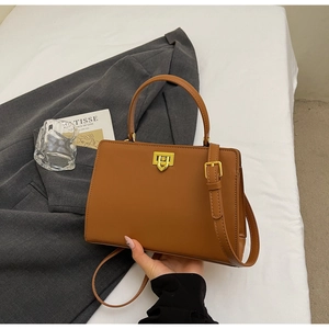 Detail of a brown leather crossbody bag featuring a gold buckle and textured PU material