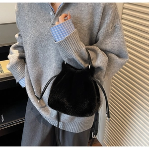 Detail of black plush bucket bag showing soft faux fur texture and silver metal hardware