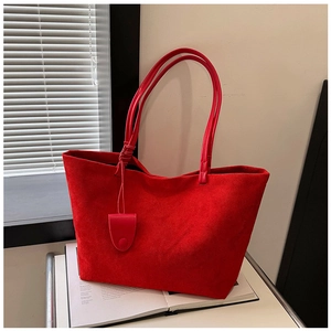 Detail of red suede tote bag texture with long handle on a white book backdrop