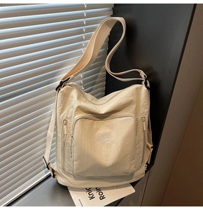 Close-up of off-white multi-pocket tote bag with broad strap on a sunny windowsill