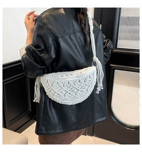Close-up of white bohemian woven crescent bag with decorative long fringes and tassels