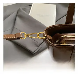 Dettaglio ravvicinato dei ganci dorati e della cerniera di una borsa in pelle marrone