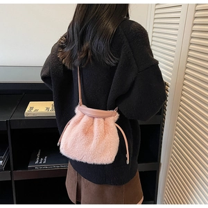 Pink plush faux fur drawstring bucket bag with leather strap on a model back view