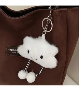 Close-up of a white plush cloud keychain with a smile on a brown tote bag