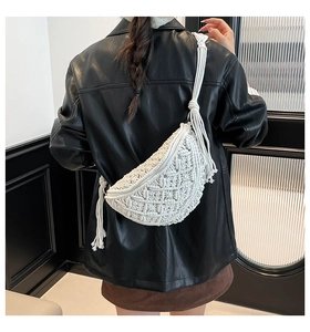 Detail of bohemian white hand-woven crescent bag with intricate knit patterns and long fringes
