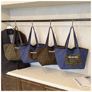 Detail of trendy leopard print and denim canvas tote bags hanging in a stylish studio