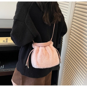 Detail of pink plush bucket bag with drawstring closure and leather shoulder strap
