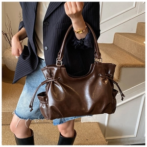 Detail view of brown tote bag side with drawstring and smooth leather texture