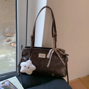 Detail of dark coffee shoulder bag with embossed patterns and white star plush charm