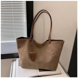 Close-up of brown suede tote bag texture with leather strap and hanging ornament