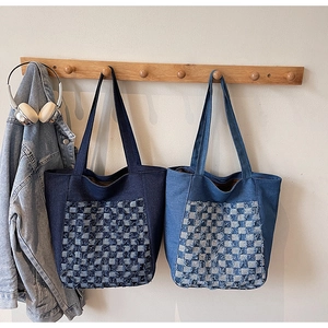 Détail de sacs fourre-tout en denim avec poches à carreaux et bords effilochés en bleu