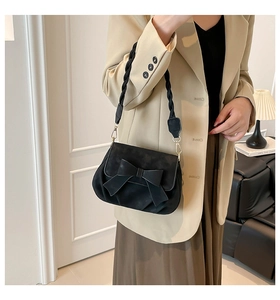 Dettaglio della borsa a sella nera opaca con grande fiocco e tracolla in tessuto su modella