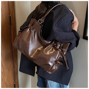 Detail of dark brown oil wax leather tote featuring side pockets and drawstring closure