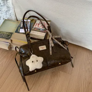 Close-up of retro brown PU leather shoulder bag with embossed bear patterns and ribbon