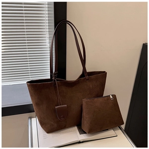 Detail of dark brown suede tote bag set with matching inner pouch on white shelf