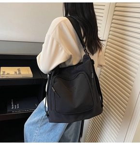 Detail of minimalist black nylon tote bag with functional multiple zipper pockets