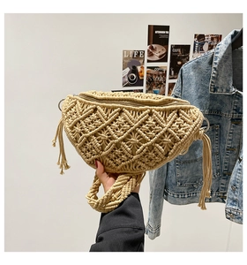 Detail of bohemian woven beige crescent bag with tassel accents and lattice pattern