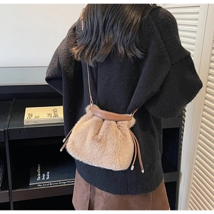 Detail of light brown plush bucket bag with leather drawstring and soft faux fur texture