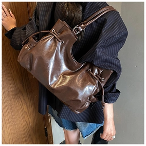 Detail of coffee brown oil wax leather tote bag with drawstring on a fashion model