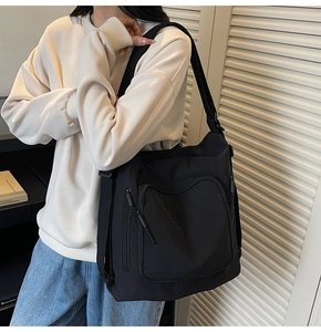 Detailed view of black nylon tote bag with functional zipper pocket and adjustable strap