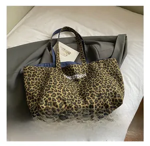 Detail of leopard print canvas tote bag featuring white lettering and blue lining