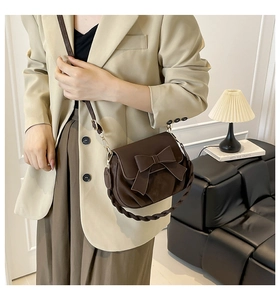 Close-up of brown matte PU shoulder bag with decorative bow and woven handle detail
