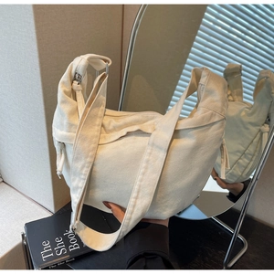 Détail du sac demi-lune en toile beige minimaliste avec fermeture éclair métallique
