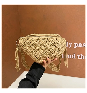 Close-up of handmade straw woven waist bag with beige cotton rope and fringe detail
